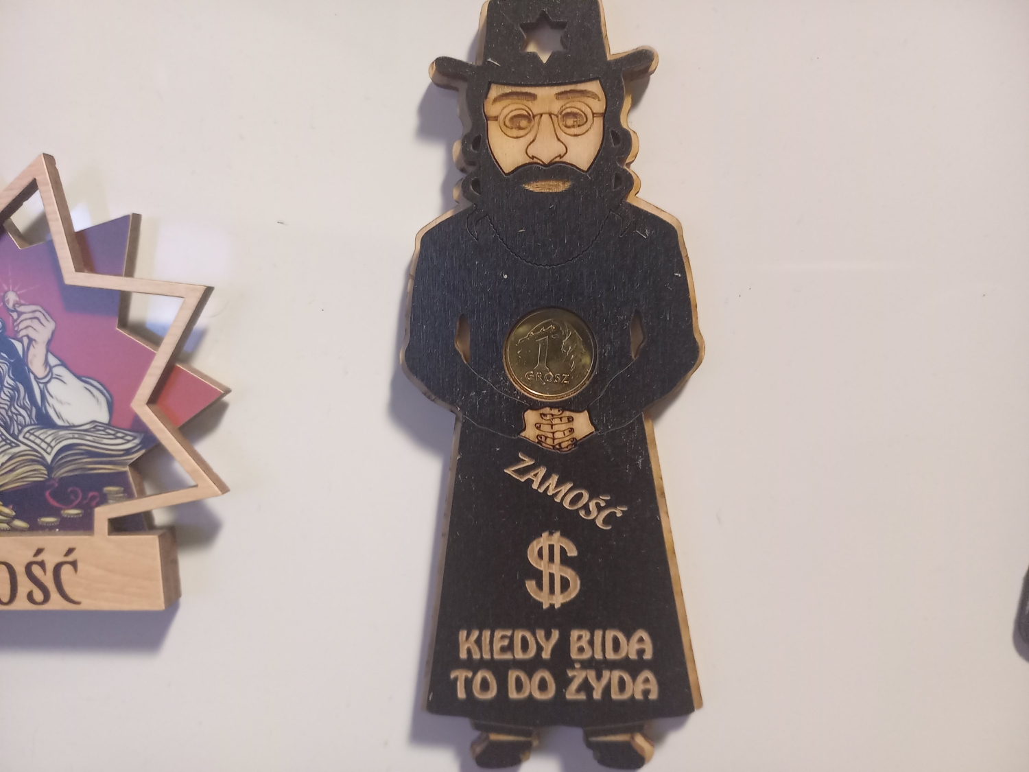 Magnes z Zamościa z tradycyjnym żydem na szczęście oraz osadzoną w nim 1groszówką